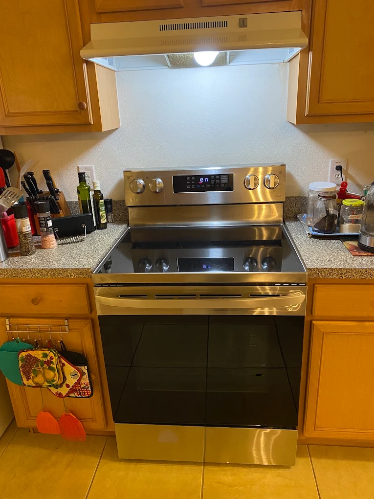 Stainless steel LG electric range between wood kitchen cabinets