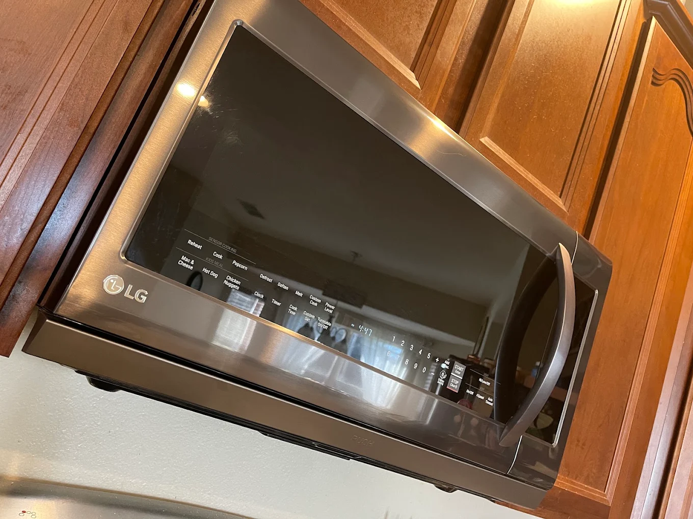 Stainless steel LG microwave installed beneath wood kitchen cabinets