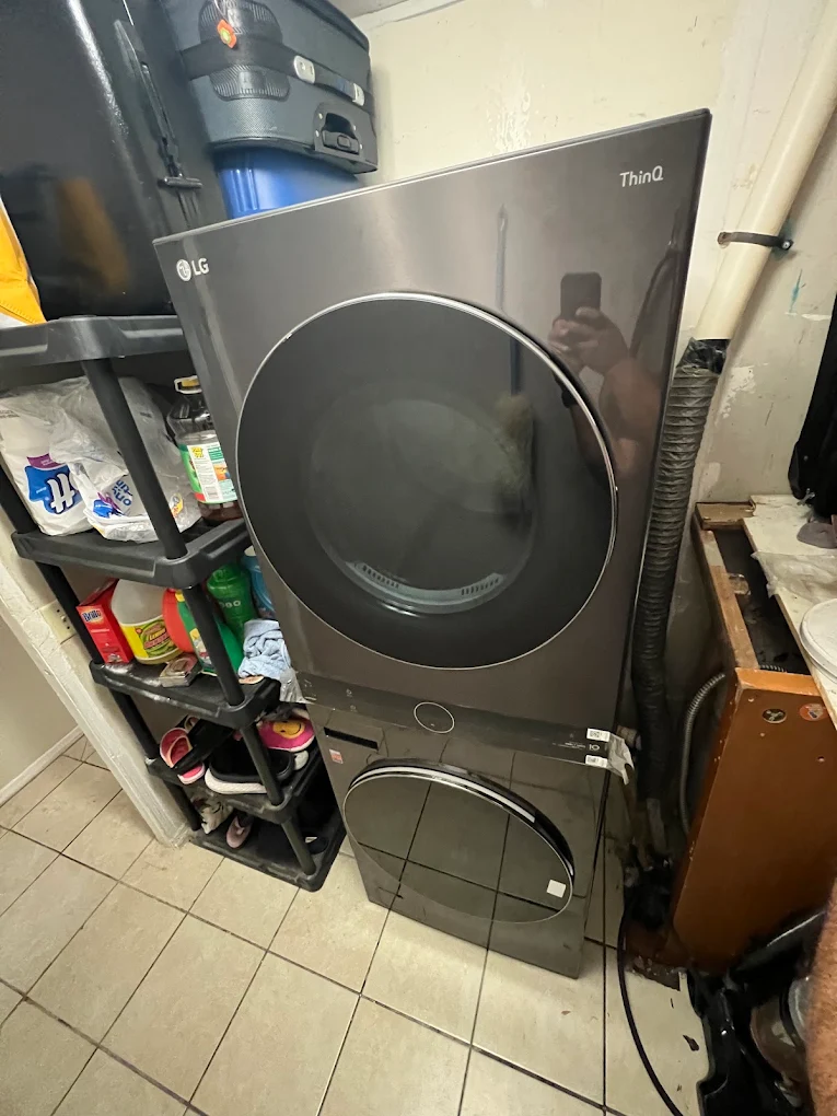 Dark LG laundry tower installed beside storage shelves