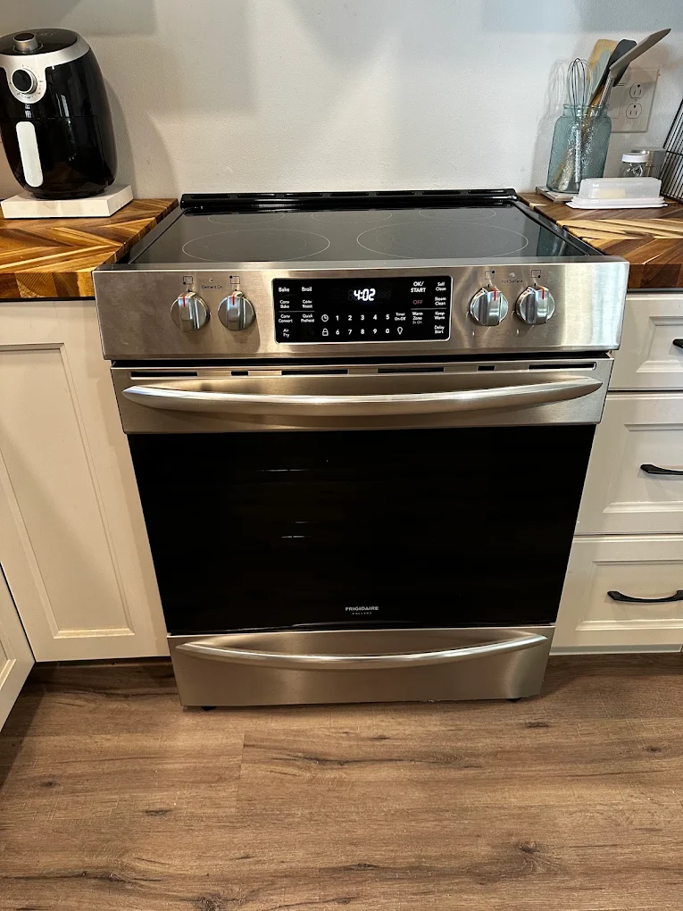 Stainless steel Frigidaire electric range between white kitchen cabinets