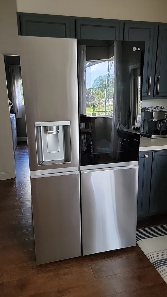 LG refrigerator with a glass door panel installed beside dark kitchen cabinets